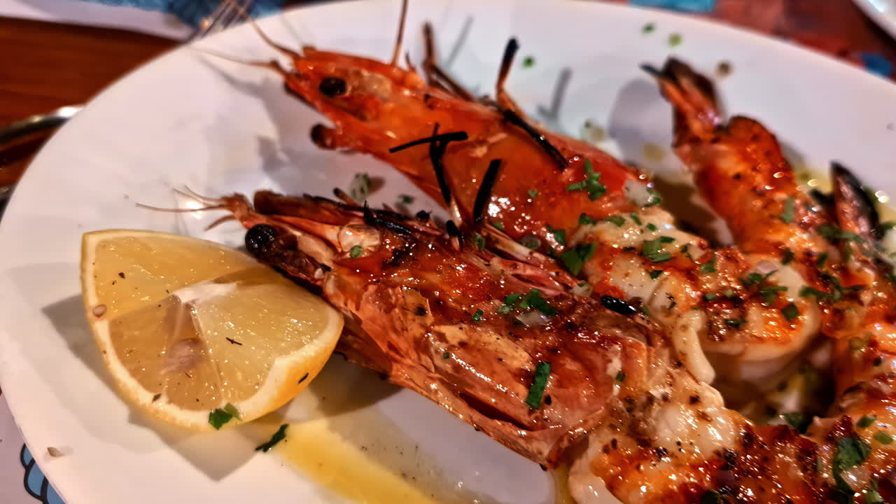 Profile view of big prawn appetizer with lemon juice squeezed on it.