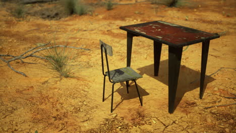 table and chair on dry and cracked ground under bright sun