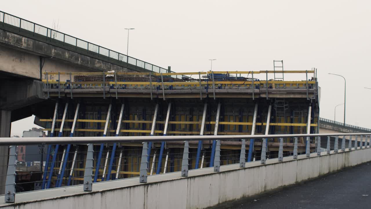 Static shot of a column under construction next to an old flyover, showcasing urban infrastructure upgrades
