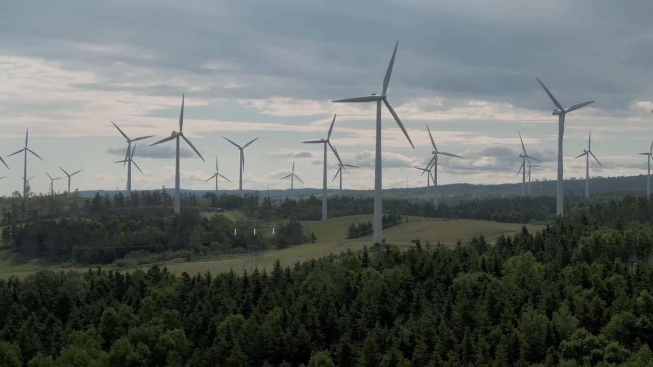 Overflying The Lush Green Forest Towards The Wind Turbines - Renewable Energy Wind Power Under A Cloudy Sky. - aerial push in shot