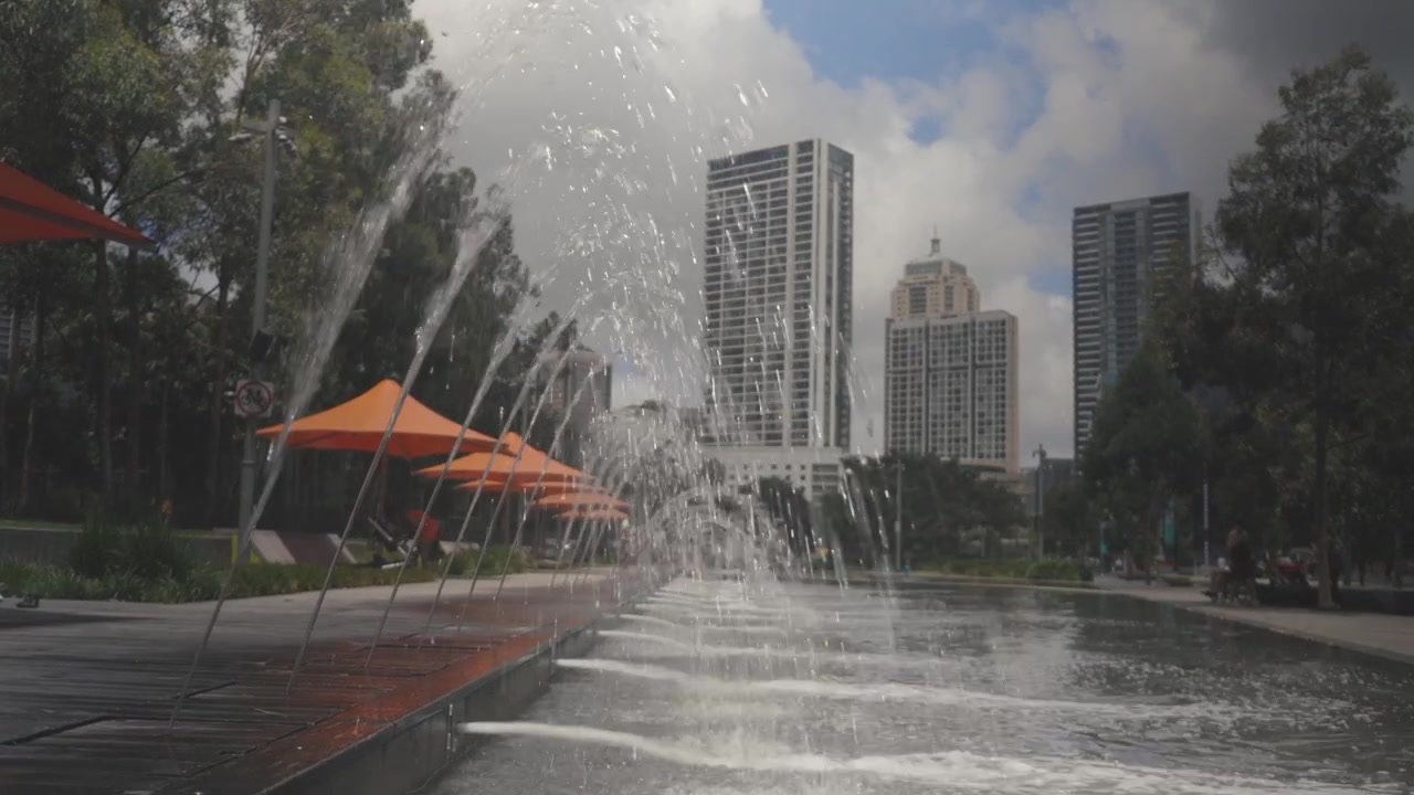 Fuente en Darling Harbour, Sídney, Australia, vista a través del agua en 4K.
