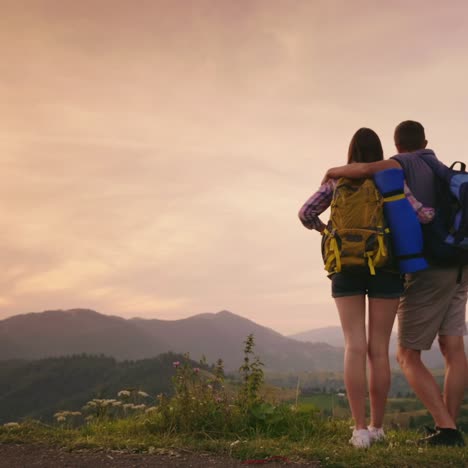 A-Young-Couple-Of-Tourists-With-Backpacks-Look-Up-At-The-Airplane-In-The-Sky-2