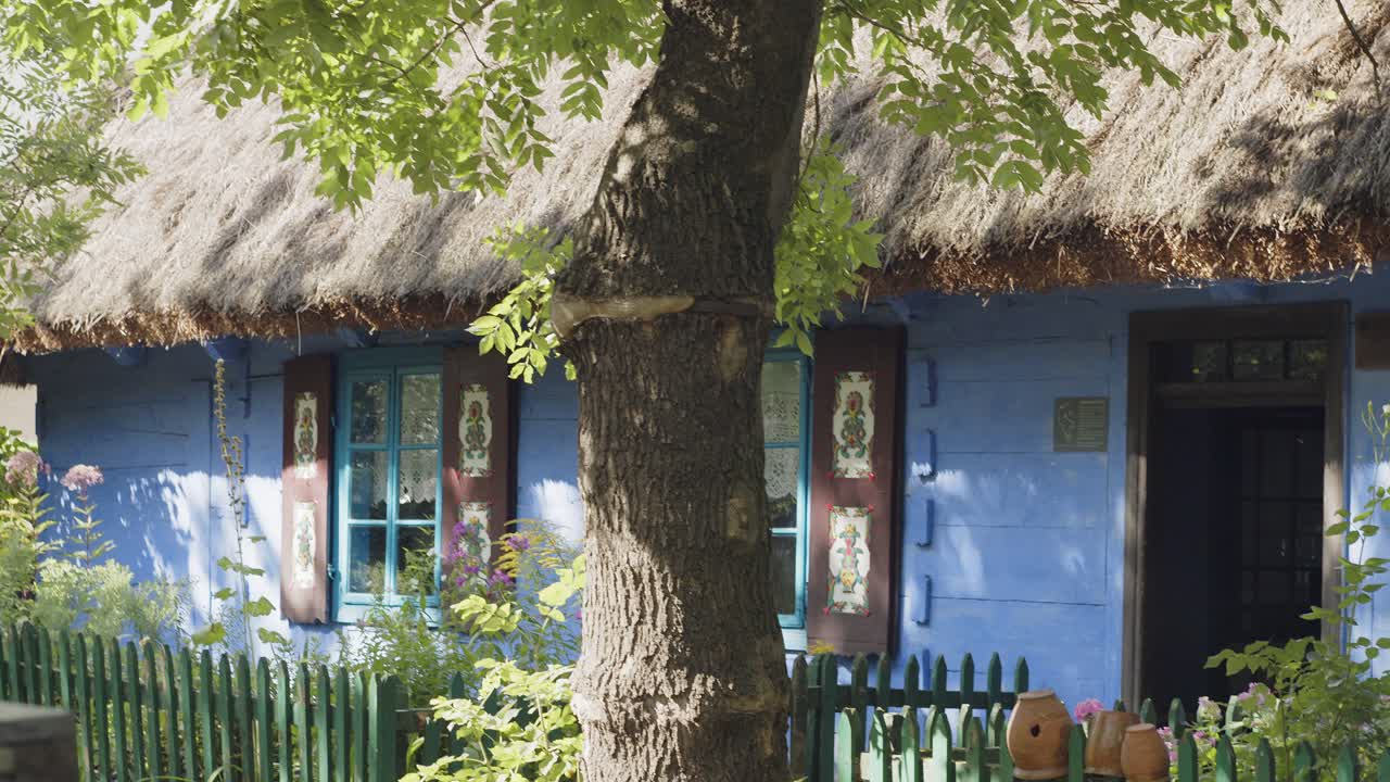 viejas vasijas de arcilla colgadas en una cerca de madera frente a la cabaña azul del siglo xix en europa del este