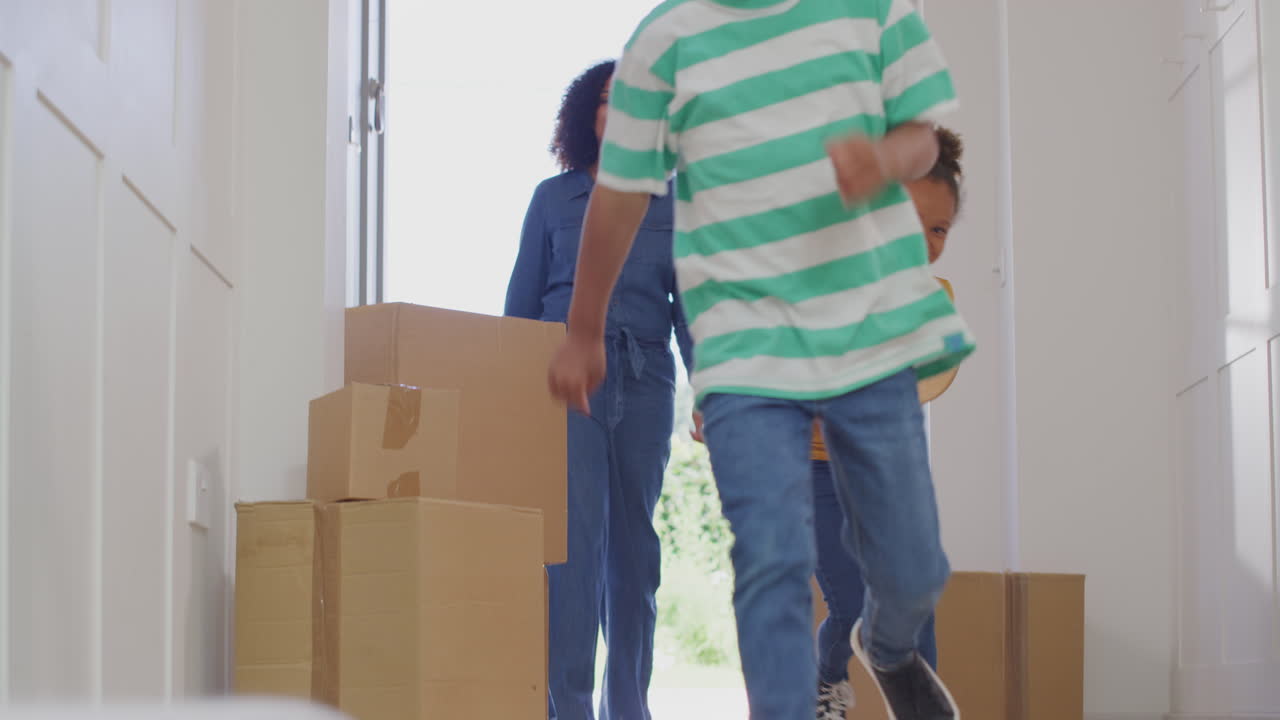 niños emocionados ayudando a la madre a llevar cajas a la nueva casa en el día de mudanza