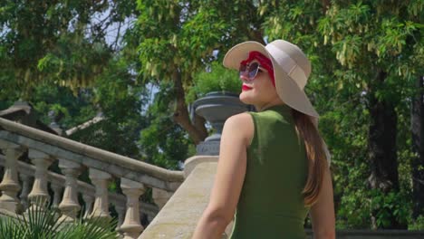 imágenes impresionantes de una niña con un vestido verde con sombrero sube las escaleras, observando alegremente la cascada monumental-la fuente de gaudí y el parque de la ciudadela