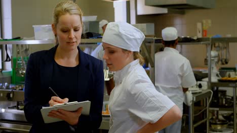 female manager and female chefs discussing over clipboard 4k