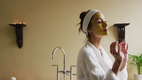 mujer biracial con máscara facial mirando a la cámara y sonriendo