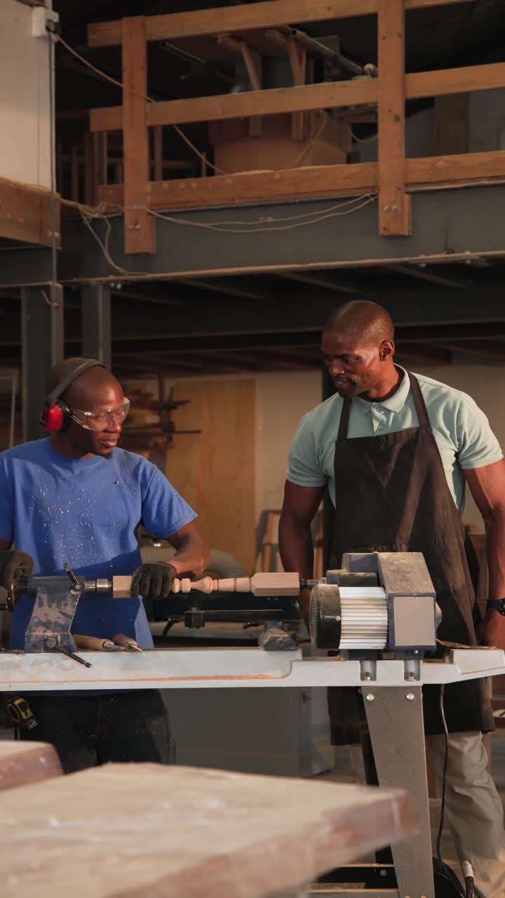 Vertical video: Male mentor, trainee walking to lathe shop after hearing lathe, checking spindle
