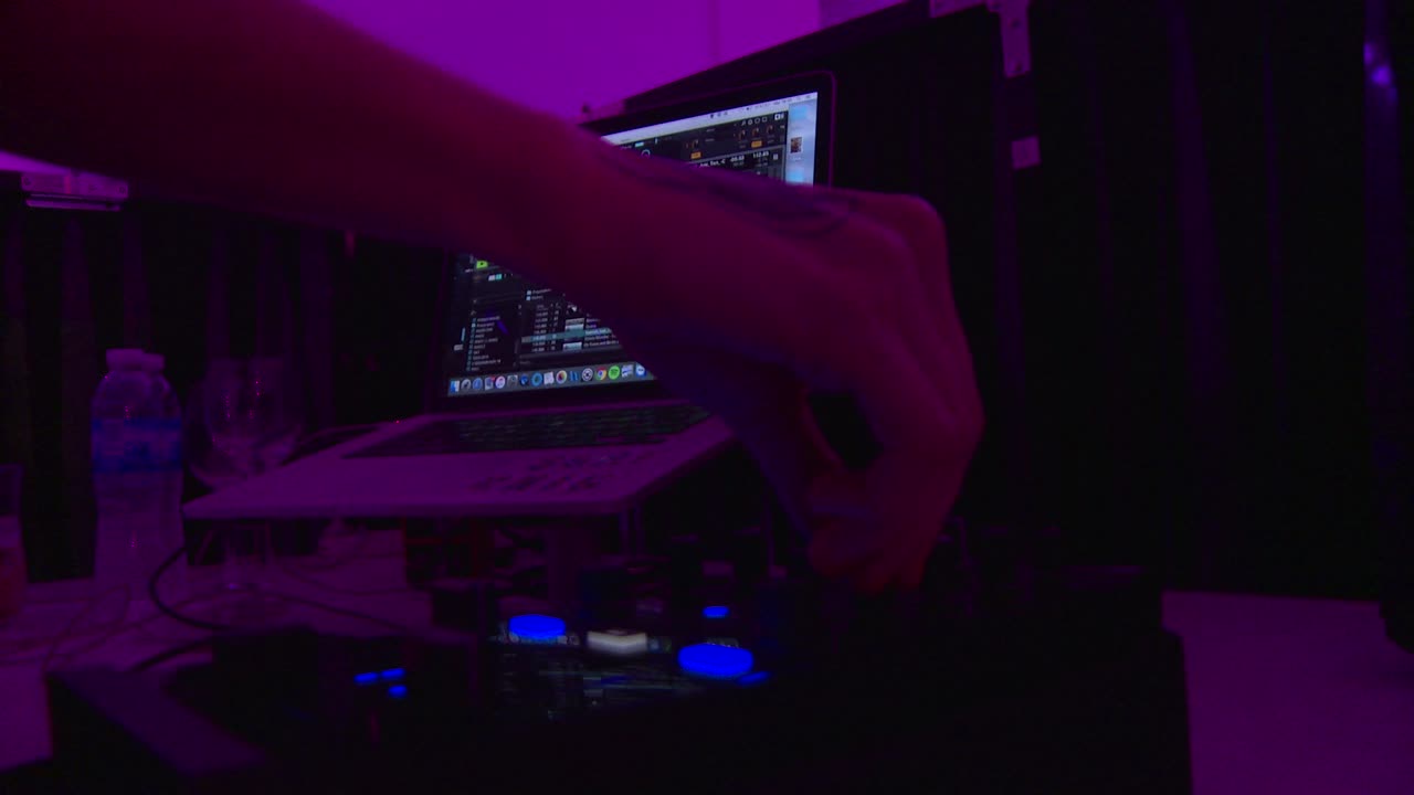 DJ Mixing Music on Laptop and Controller in Dark Club