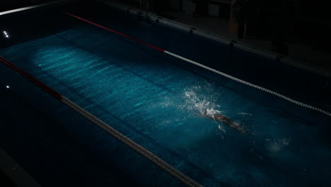 a person swimming in a pool at night