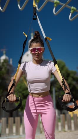 woman doing trx workout in a park