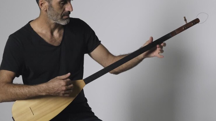 Middle eastern man playing Kopuz which is a string instrument named Baglama with three strings on a white background.