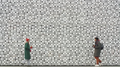 two people talking outdoors in front of a modern building