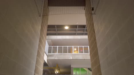 hvac system in ceiling of hallway in underground parking garage in city moving towards opening and stairs to other levels