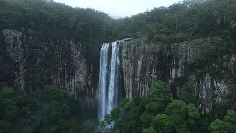 panoramic view of a majestic waterfall spilling down a tropical rainforest covered mountain