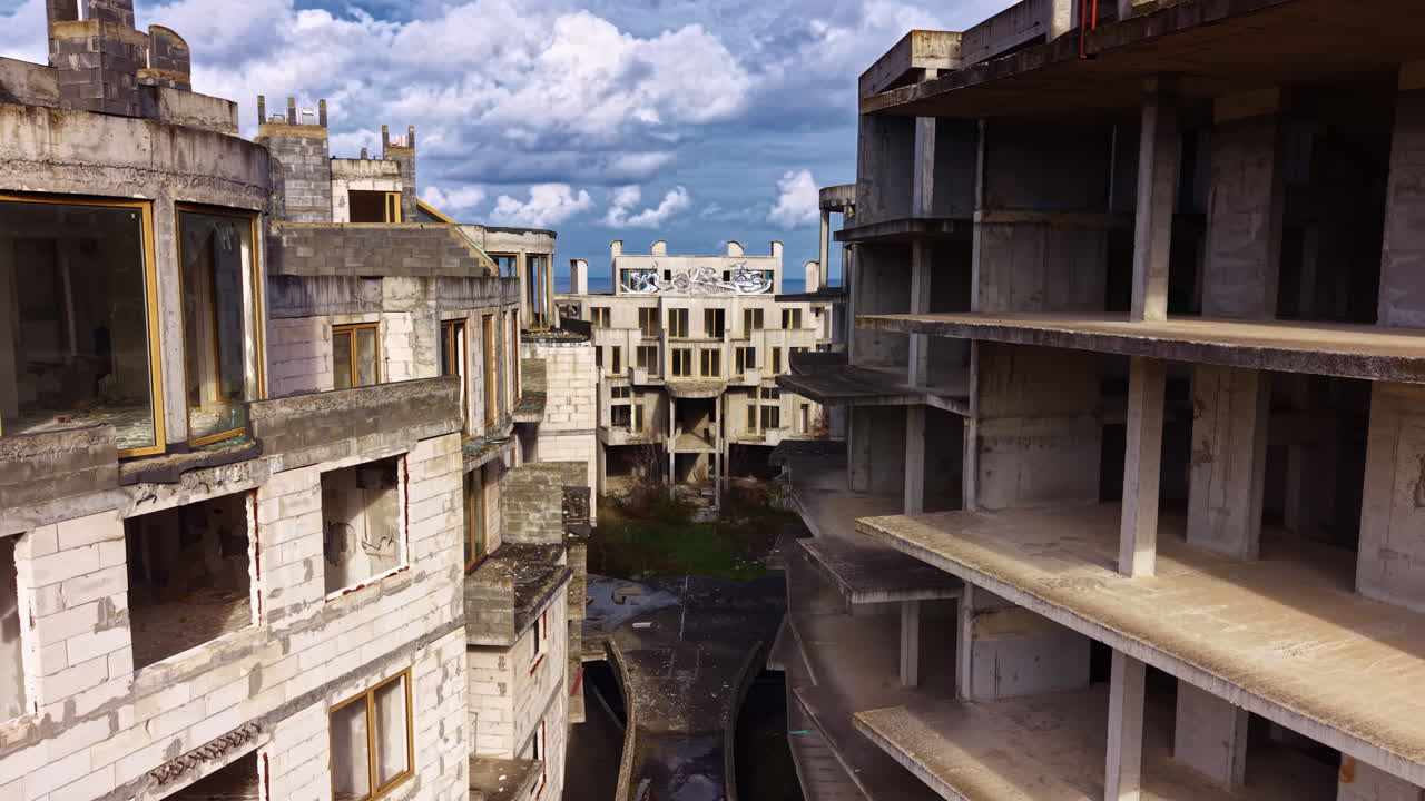 Em meio a edifícios em ruínas, sombras de um bairro esquecido se erguem sob um céu dramático repleto de nuvens rodopiantes e vestígios de um passado vibrante.