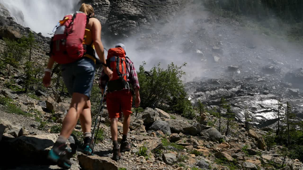 vista trasera de una joven pareja de excursionistas caucásicos con mochila caminando en el bosque 4k