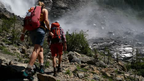 Vista-Trasera-De-Una-Joven-Pareja-De-Excursionistas-Caucásicos-Con-Mochila-Caminando-En-El-Bosque-4k