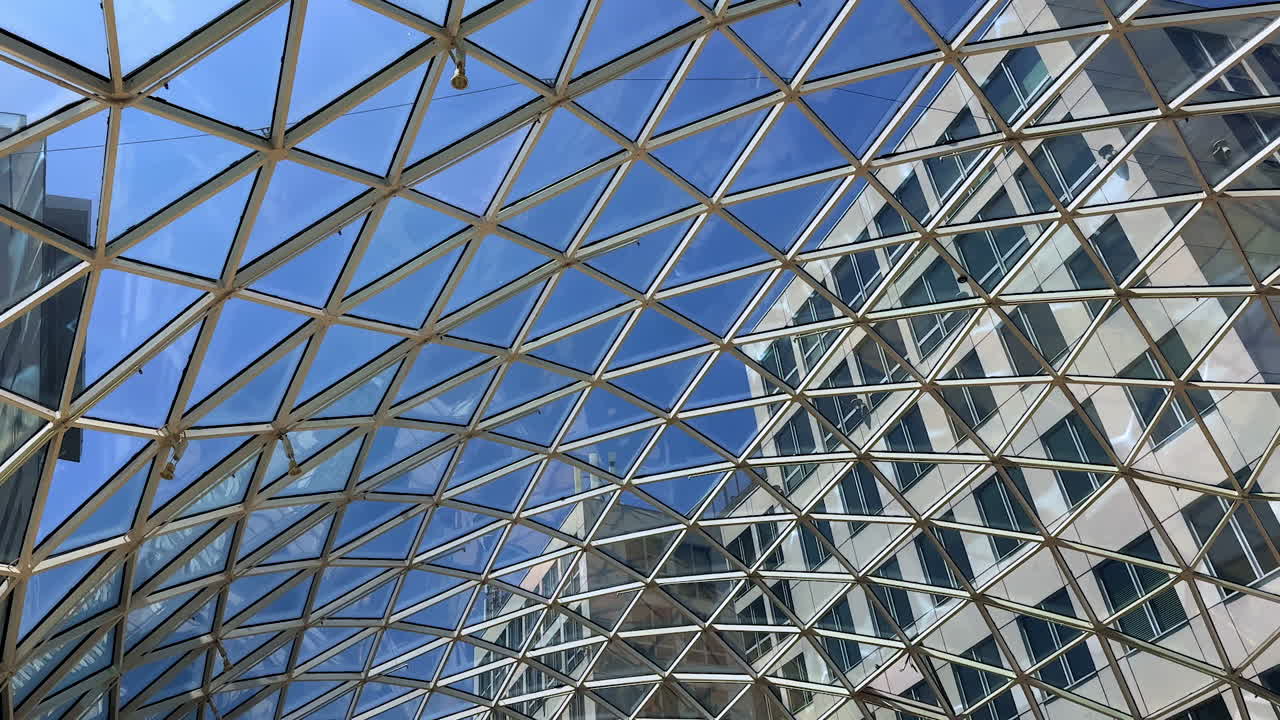 Glass cupola of the building with the view on the blue sky. Low angle perspective on the buildings outside