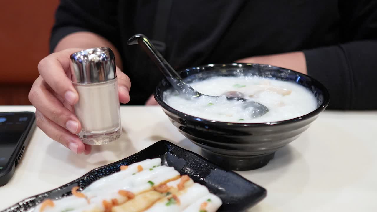 Adding seasoning to congee with deep-fried dough sticks