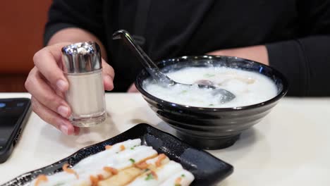 adding seasoning to congee with deep-fried dough sticks