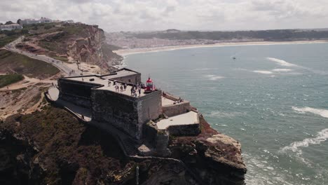 red lighthouse of nazare or nazaré and gulf coastline in background