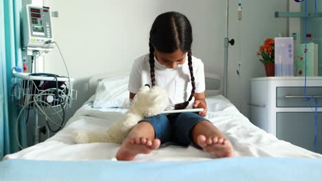 girl using digital tablet on bed