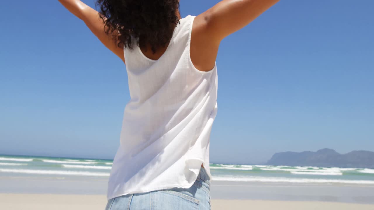 mujer de pie con los brazos extendidos en la playa 4k