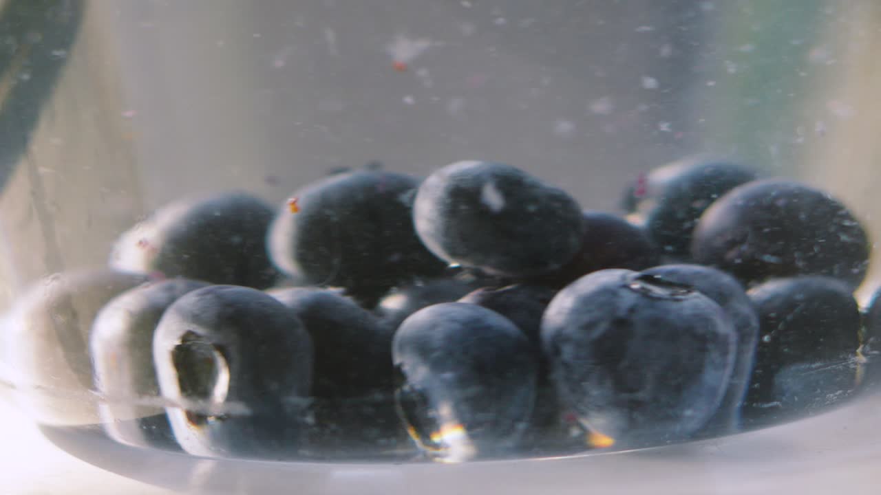 Clean Fresh Blueberries Spinning in Glass Bowl Full of Water. Washed Fruit Ripe and Ready to Eat. Delicious Food High in Nutritious Fibre and Magnesium