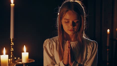 girl praying in front of candles