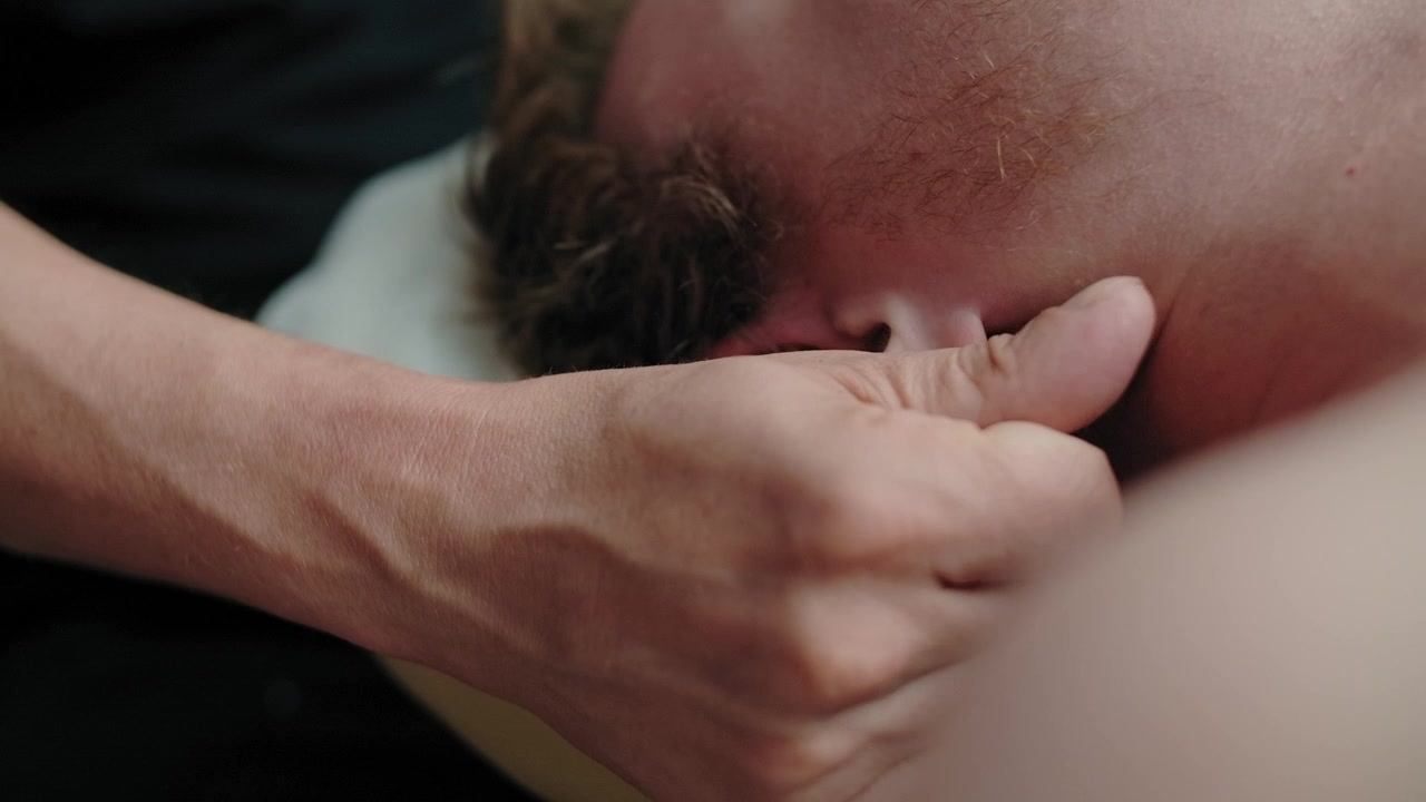 Professionel massageterapeut udfører øremassage på klient