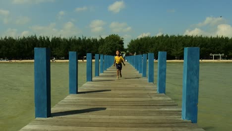 little girl running on the beach bridge with the sun coming from the side so that a body shadow appears