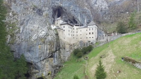 Drone-shot-of-mysterious-Predjama-castle,-built-in-a-cave-mouth-in-the-mountains-of-Slovenia