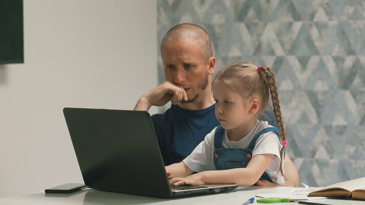 Ayah yang kebingungan bersama putrinya mengerjakan pekerjaan rumah di laptop modern.