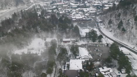 ciudad cubierta de nieve de okuhida hirayu con humo de fuentes termales onsen cerca de gifu, japón