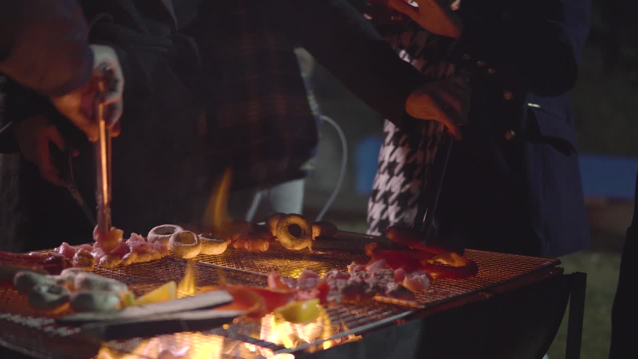 Persone in piedi davanti al barbecue che bevono e grigliano funghi, salsicce, pollo, melanzane, davanti alla casa in un giardino