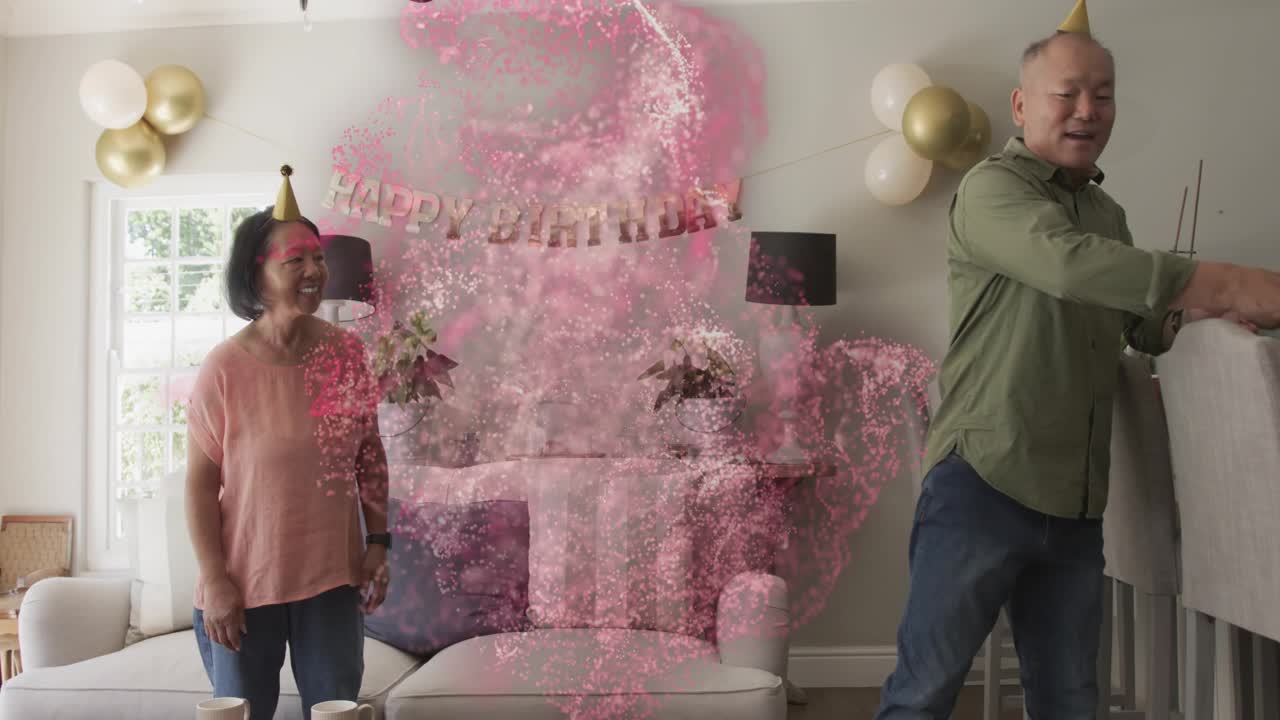 Man carrying mugs placing cake in home, woman smiling, pink swirl sweeping over couple birthday