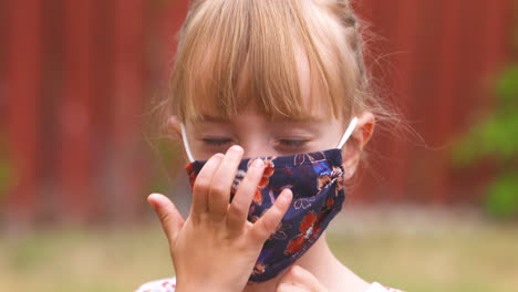 cute little girl smiles and puts on her face mask