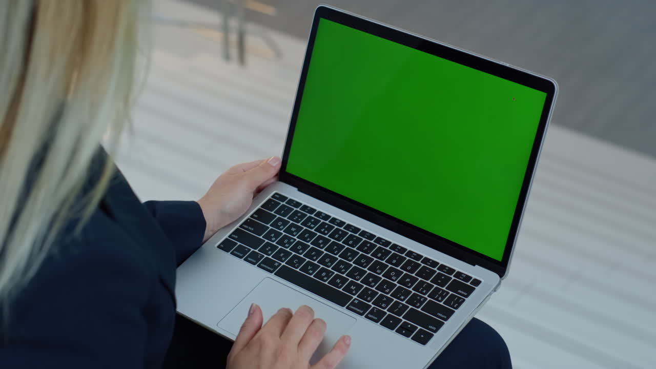 Libero professionista che naviga nell'applicazione per laptop con greenscreen in primo piano sul luogo di lavoro remoto