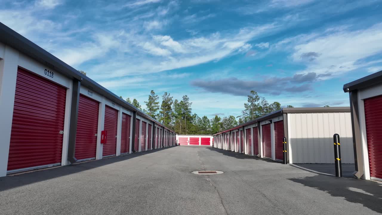 Red garages in industrial district of american town. Sunny path in autumn season. Self Storage buildings in red colors. Aerial dolly forward movement