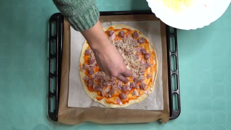 vista aérea de mujer colocando queso en pizza casera