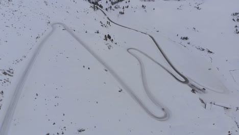 aerial drone view overlooking a car on a snowy mountain road, winter in austria