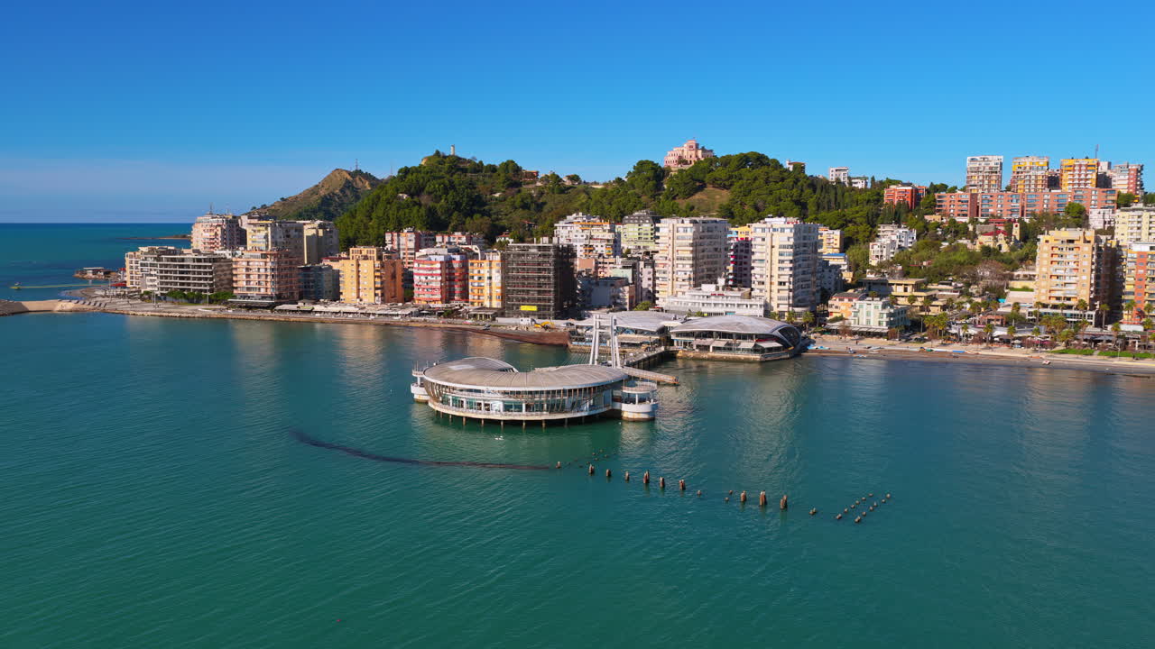 Aerial drone view of the iconic circular Rotonda building extending over the turquoise waters of the Adriatic Sea in Durres, Albania