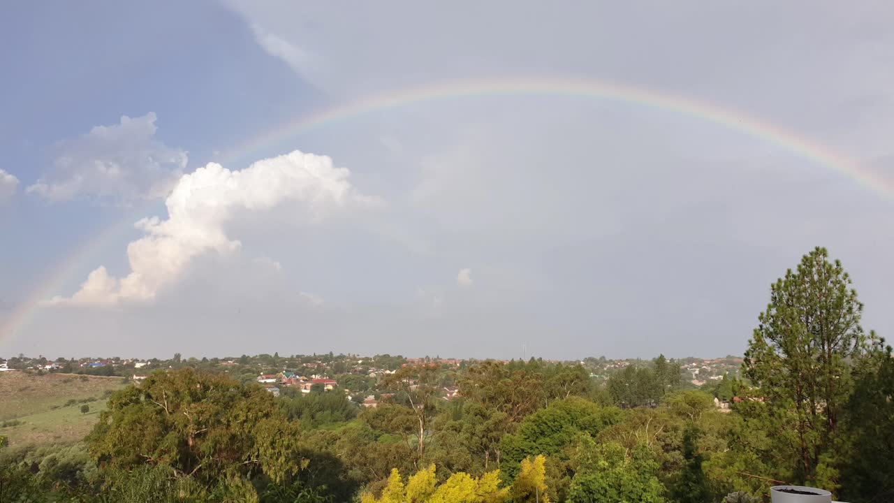 lapso de tiempo con el arco iris después de una tormenta mientras las nubes se alejan y el sol brilla sobre el barrio suburbano de sudáfrica