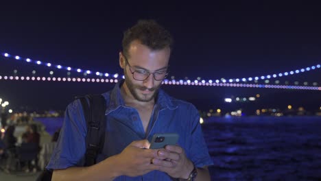 joven usando el teléfono junto al mar. noche.