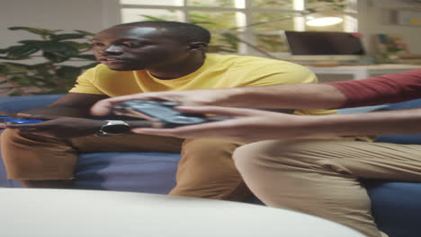 two men playing video games on a couch