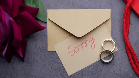 note with the sorry word next to a wedding ring