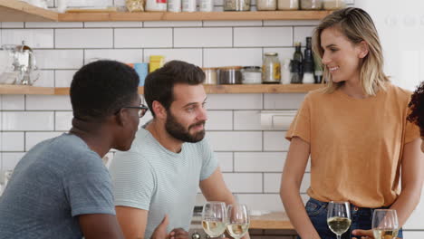 dos parejas relajándose en la cocina alrededor del mostrador de la cocina en casa y bebiendo vino juntos