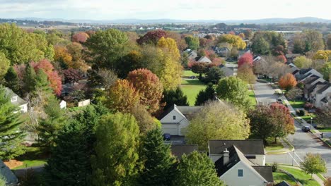 aerial establishing shot of upscale suburban homes in neighborhood community during colorful autumn fall foliage