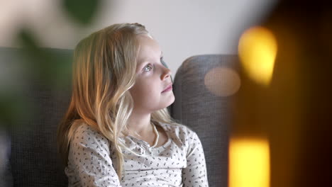 young-girl-sitting-on-sofa,-contemplative-and-listening